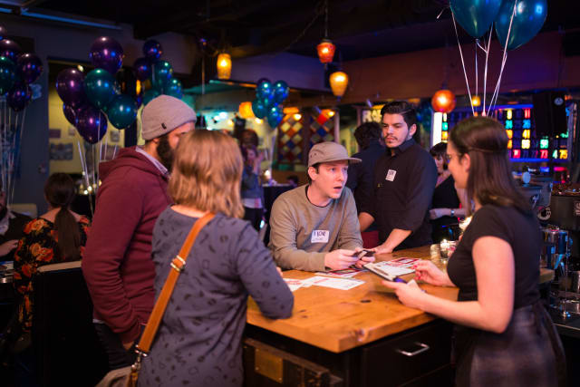 Group of attendees engaging at a bar during the Love Bomb 2017 event, with colorful balloons and festive lighting, supporting My Voice Music nonprofit.